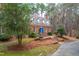 Charming brick home with blue double doors, dormer windows, and lush greenery, nestled on a tree-lined lot at 10726 Trego Trl, Raleigh, NC 27614