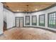 Open living room with a brick floor, natural light from large windows, a wood plank ceiling, and gray trim at 10726 Trego Trl, Raleigh, NC 27614