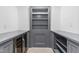 Walk-in pantry features custom gray cabinets, shelves, built-in wine fridge and beige-colored tile flooring at 10726 Trego Trl, Raleigh, NC 27614