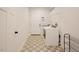 Well-lit laundry room featuring a washer, dryer, patterned tile flooring, and a wire storage shelf at 129 Edgefield Dr, Sanford, NC 27332