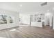 Open-concept living area featuring wood-look floors, light gray walls, large windows, and a view into the kitchen at 185 White Birch Ln, Angier, NC 27501