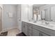 Bathroom featuring double sinks, gray cabinets, and a large, bright mirror at 193 Millennium Dr, Pittsboro, NC 27312