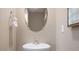 Simple powder room featuring a pedestal sink, oval mirror, and neutral decor at 2168 Monk Dr, Haw River, NC 27258