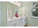 A bright bathroom featuring double sinks, white cabinetry, a large mirror, and natural light from a window at 2302 Wispy Green Ln, Raleigh, NC 27614