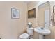 A cozy half-bathroom featuring a pedestal sink, toilet, decorative artwork, and neutral paint at 2302 Wispy Green Ln, Raleigh, NC 27614