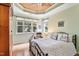 A relaxing bedroom featuring a tray ceiling with ceiling fan, a sitting area, and plenty of natural light at 2302 Wispy Green Ln, Raleigh, NC 27614