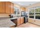A charming kitchen featuring wood cabinets, granite countertops, stainless steel appliances, and natural light from two windows at 2302 Wispy Green Ln, Raleigh, NC 27614