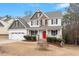 Inviting two-story home with a charming front porch, a red door and manicured landscaping at 244 Winding Oak Way, Clayton, NC 27520