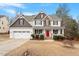 Inviting two-story home with a charming front porch, a red door and manicured landscaping at 244 Winding Oak Way, Clayton, NC 27520