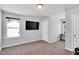 Carpeted bedroom with a TV mounted on the wall, two windows allowing natural light, and two doors at 286 Beacon Hill Rd, Lillington, NC 27546