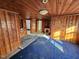 Wood-paneled living room featuring a vintage blue carpet and multiple doorways in need of repair at 306 Martin Luther King Jr Dr, Smithfield, NC 27577