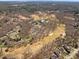 Aerial view showcases the estate's extensive greenery, golf course, and pool against a backdrop of lush trees and blue skies at 4405 Turnberry Cir, Durham, NC 27712