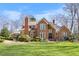 Stunning brick home boasts large windows, detailed trim, lush landscaping, and a manicured lawn under a bright, blue sky at 4405 Turnberry Cir, Durham, NC 27712