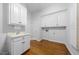 Bright laundry room with white cabinets, sink, and hardwood floors at 4405 Turnberry Cir, Durham, NC 27712