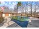 A partially covered swimming pool, surrounded by a concrete deck, a brick wall and a lush backyard at 4405 Turnberry Cir, Durham, NC 27712