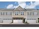 New construction townhome with stone accents, neutral siding, and attached garages under a cloudy, bright blue sky at 6966 Doddridge Ln # 12, Cary, NC 27519