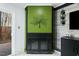 Modern fireplace featuring a green accent wall, wood-look paneling, and sleek black mantle at 7205 Sandy Creek Dr, Raleigh, NC 27615