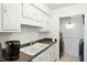 Clean laundry room with white cabinets, black appliances, and convenient access at 7205 Sandy Creek Dr, Raleigh, NC 27615