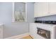 Well-lit laundry room featuring white cabinets, countertops, and modern washer and dryer at 9700 Pentland Ct, Raleigh, NC 27614