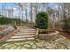 Backyard stone steps lead to tranquil pond with water feature amidst lush greenery and mature trees at 10729 Trego Trl, Raleigh, NC 27614