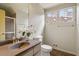 Clean bathroom with a stone countertop vanity, shower, and bright window at 10729 Trego Trl, Raleigh, NC 27614