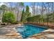 A backyard pool with surrounding stone patio offers a serene oasis amidst lush greenery and mature trees at 10729 Trego Trl, Raleigh, NC 27614