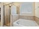 Bathroom featuring a soaking tub, glass enclosed shower, and tiled walls with a neutral color palette at 117 Oak Rise Ln, Fuquay Varina, NC 27526