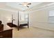 Bright main bedroom featuring a four-poster bed, neutral decor, and carpeted flooring at 117 Oak Rise Ln, Fuquay Varina, NC 27526