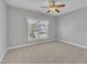 A bright bedroom featuring neutral carpet, a ceiling fan, and a large window at 12404 Beauvoir St, Raleigh, NC 27614