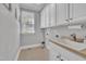 A clean and bright laundry room with white cabinetry, a sink, and tiled floors at 12404 Beauvoir St, Raleigh, NC 27614