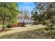View of the back of the home, with large yard, mature trees and screened porch at 1704 Cypress Dr, Henderson, NC 27536