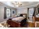 Comfortable bedroom featuring two windows, ceiling fan, hardwood floors, and wooden furniture at 1704 Cypress Dr, Henderson, NC 27536