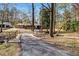 Driveway leading to a brick home surrounded by mature trees and natural landscaping at 1704 Cypress Dr, Henderson, NC 27536