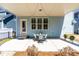 Covered patio with outdoor seating area, string lights, and a door leading to a light blue house at 201 Bluffwood Avenue, Chapel Hill, NC 27516