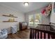 Charming Bedroom featuring a dark wood crib, changing table, and wood laminate flooring with a bright window at 309 Old Farm Dr, Graham, NC 27253