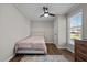 Cozy bedroom featuring hardwood floors, a ceiling fan, and a large window with natural light at 309 Old Farm Dr, Graham, NC 27253