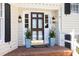 Inviting entryway with a glass-paneled door, decorative sconces, potted plants, and brick steps at 3508 Cambridge Rd, Durham, NC 27707