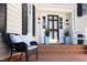 Inviting front porch with wicker chair, stylish pillows, a dark wood door, and decorative potted plants at 3508 Cambridge Rd, Durham, NC 27707