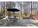 Outdoor patio with table and chairs with a black umbrella with woods in the background at 3508 Cambridge Rd, Durham, NC 27707
