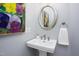 Stylish powder room featuring a pedestal sink, modern faucet, and decorative artwork, offering a refined touch at 3508 Cambridge Rd, Durham, NC 27707