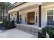Spacious covered front porch with beautiful columns, a wooden front door, and well-maintained landscaping at 5600 Abbey Grace Ln, Wake Forest, NC 27587