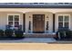 Inviting front porch showcasing a wood door flanked by decor, rocking chairs, and tasteful landscaping at 5600 Abbey Grace Ln, Wake Forest, NC 27587