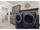 Bright laundry room with blue washer and dryer, gray cabinets, and decorative tile flooring at 5600 Abbey Grace Ln, Wake Forest, NC 27587