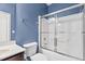 Neat bathroom featuring a blue accent wall, and a shower/tub combo with sliding glass doors at 69 Florence Dr, Clayton, NC 27527