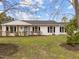Beautiful single-story house with white brick and dark shutters, complemented by a vibrant green lawn and blooming bushes at 711 Wheat Mill Rd, Durham, NC 27704