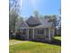 Charming cottage style home with covered porch and manicured lawn, nestled among mature trees on a sunny day at 8 Elaine Cir, Durham, NC 27703
