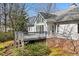 Back of home features a deck, large windows, neutral siding, and brick foundation accents, nestled within lush greenery at 8116 Windsor Ridge Dr, Raleigh, NC 27615