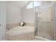 Bathroom featuring a soaking tub, glass shower, and neutral tile at 8116 Windsor Ridge Dr, Raleigh, NC 27615
