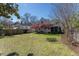 Expansive backyard featuring lush green grass, mature trees, and colorful flowering shrubs with a screened in porch at 1010 Rosehill Ave, Durham, NC 27705