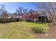 Expansive backyard featuring lush green grass, mature trees, and colorful flowering shrubs with a screened in porch at 1010 Rosehill Ave, Durham, NC 27705